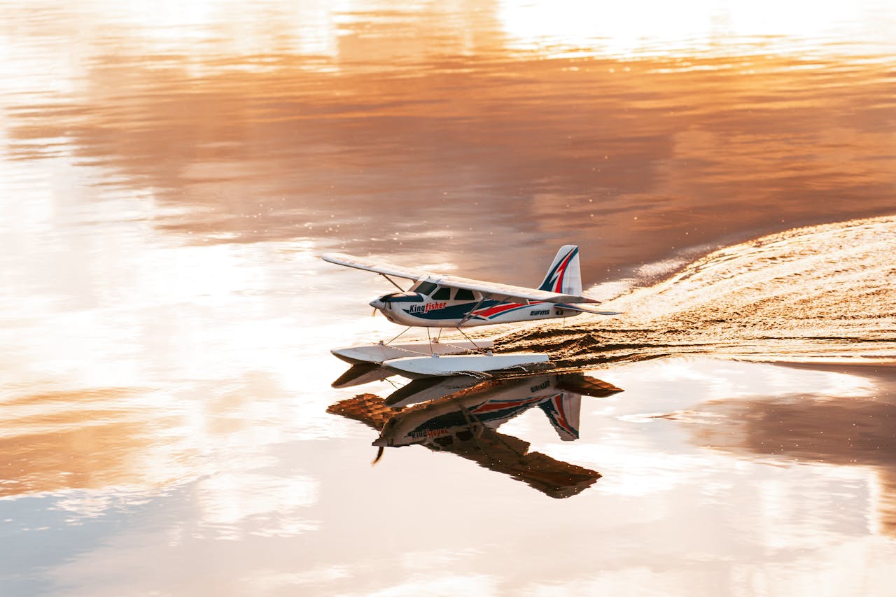 A radio-controlled seaplane glides on calm water, showcasing a serene and placid reflection.
