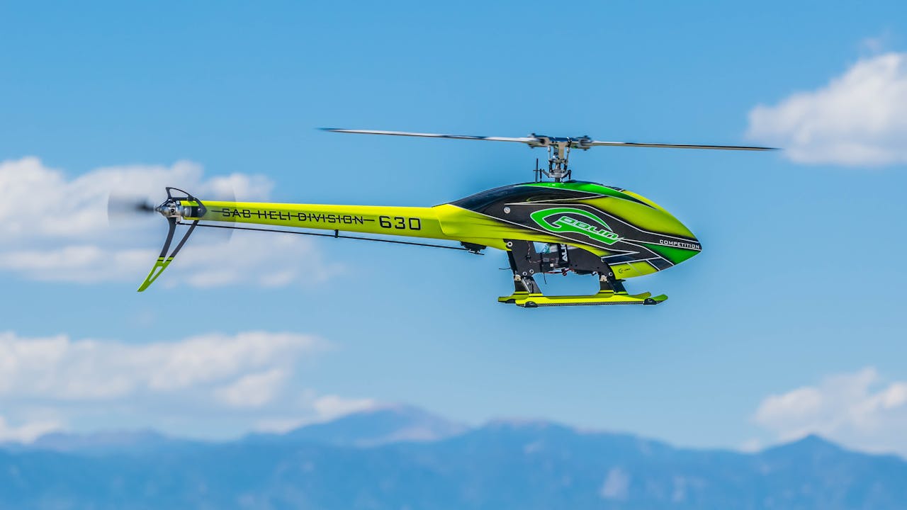 Lively RC helicopter soaring against a clear blue sky, captured mid-flight in vivid detail.
