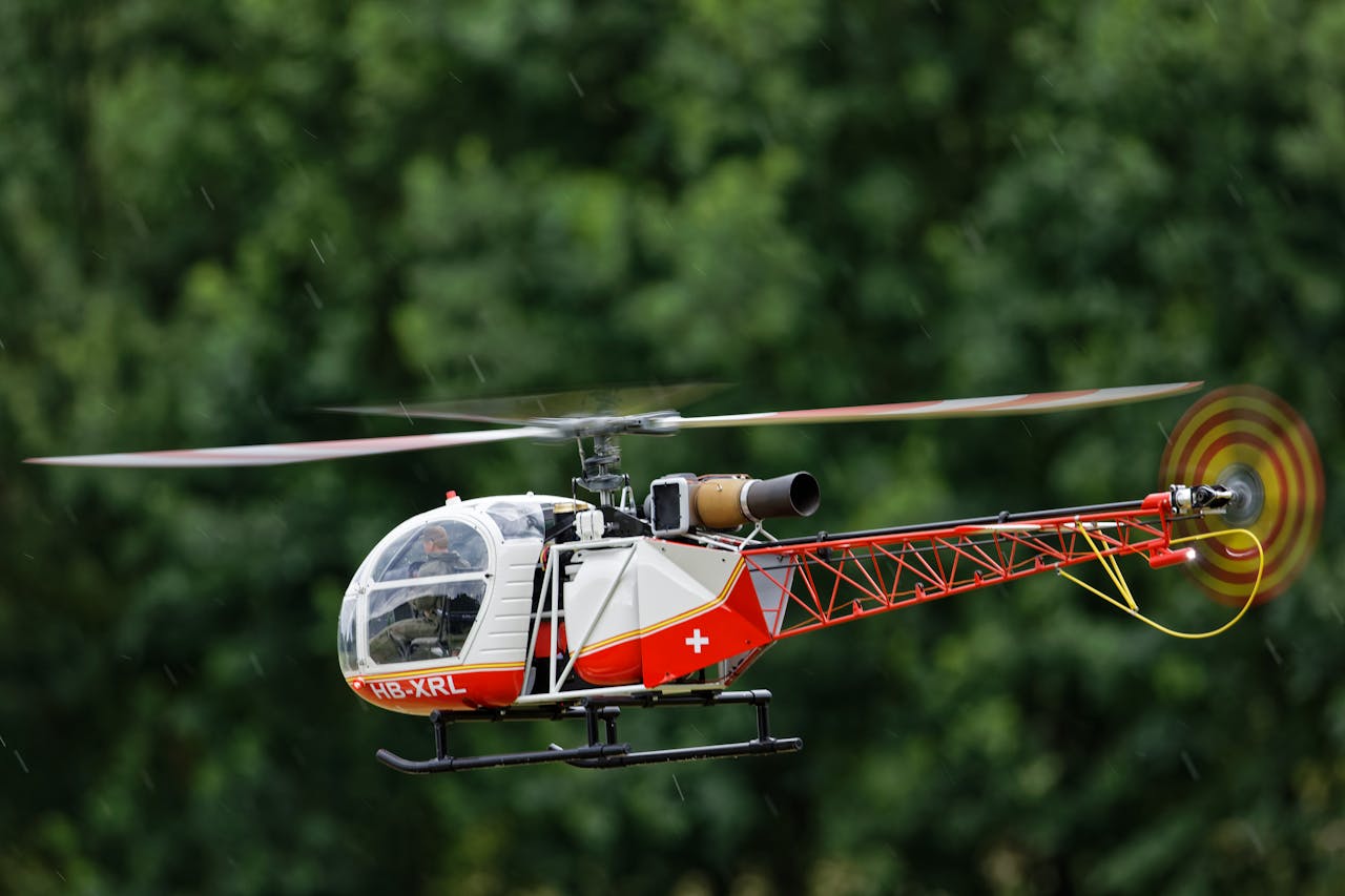 Close-up of a radio-controlled helicopter flying outdoors against greenery.